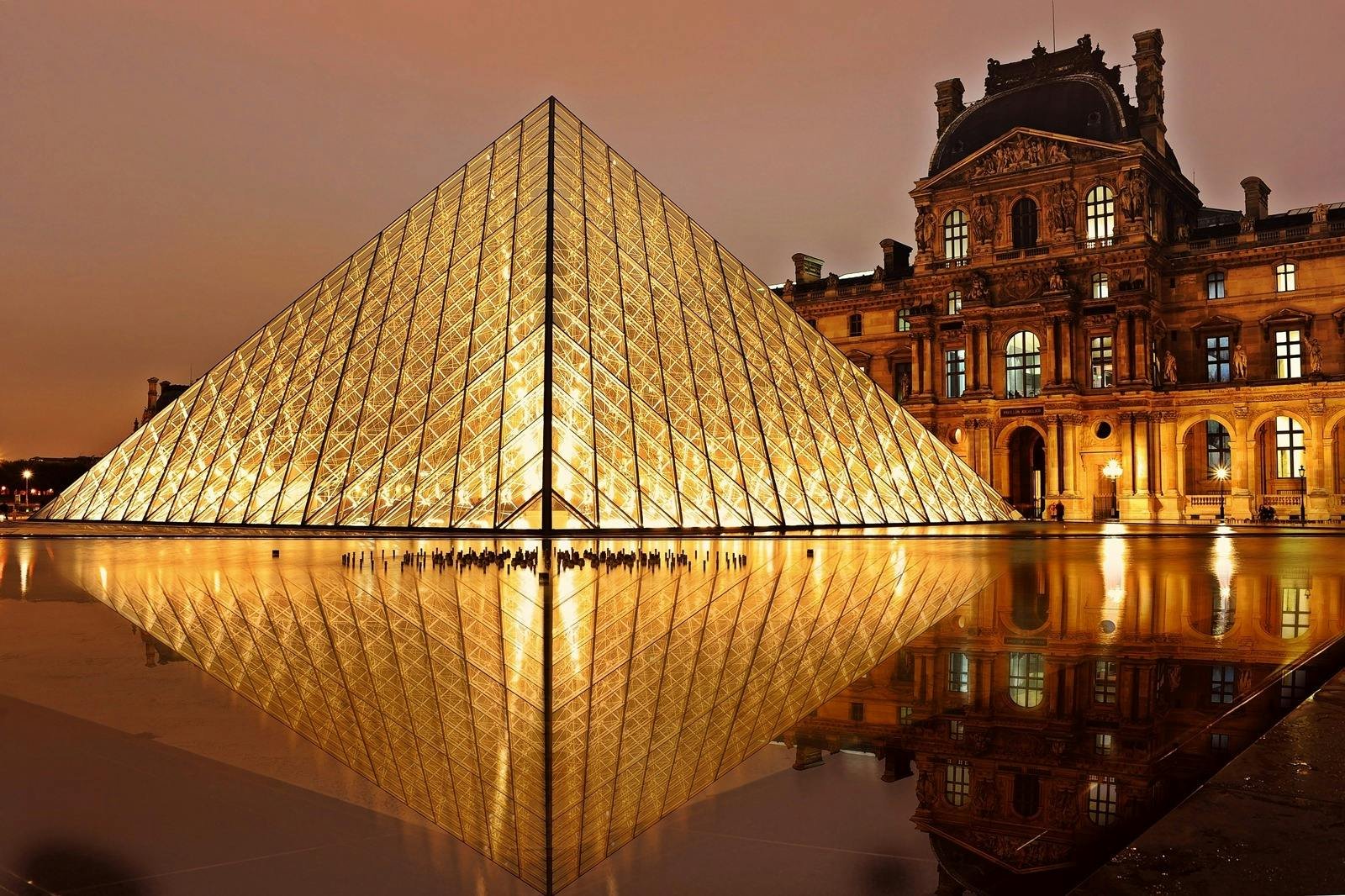 Inspirations Stunning nighttime view of the illuminated Louvre Pyramid and reflection in Paris, France.