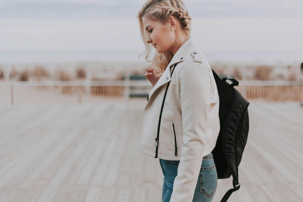 Special Offers A young woman in a leather jacket walking on a boardwalk, embracing a casual and stylish vibe.