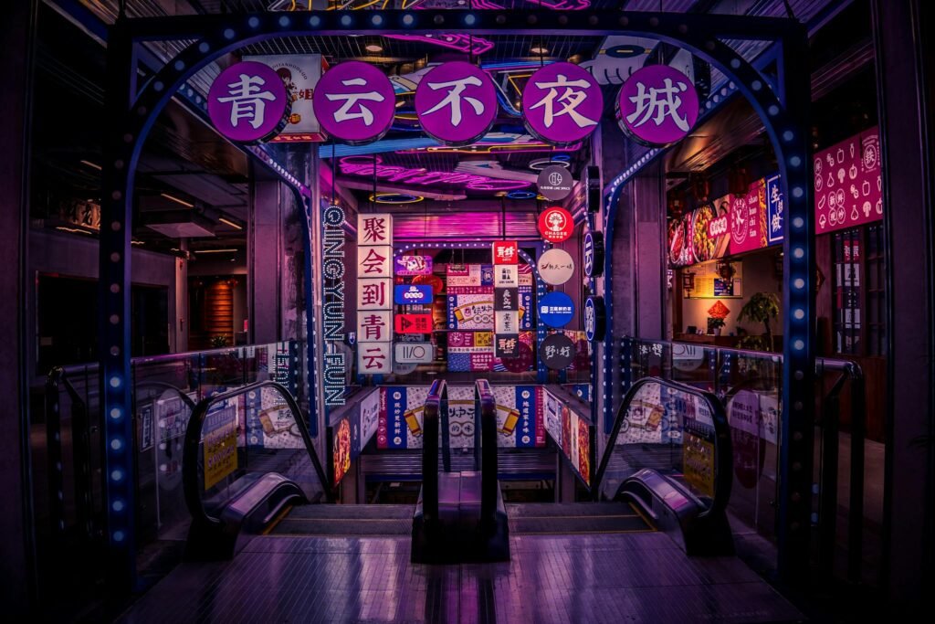 Special Offers Vibrantly lit entrance of a shopping mall with neon signs in Chinese characters and escalators.