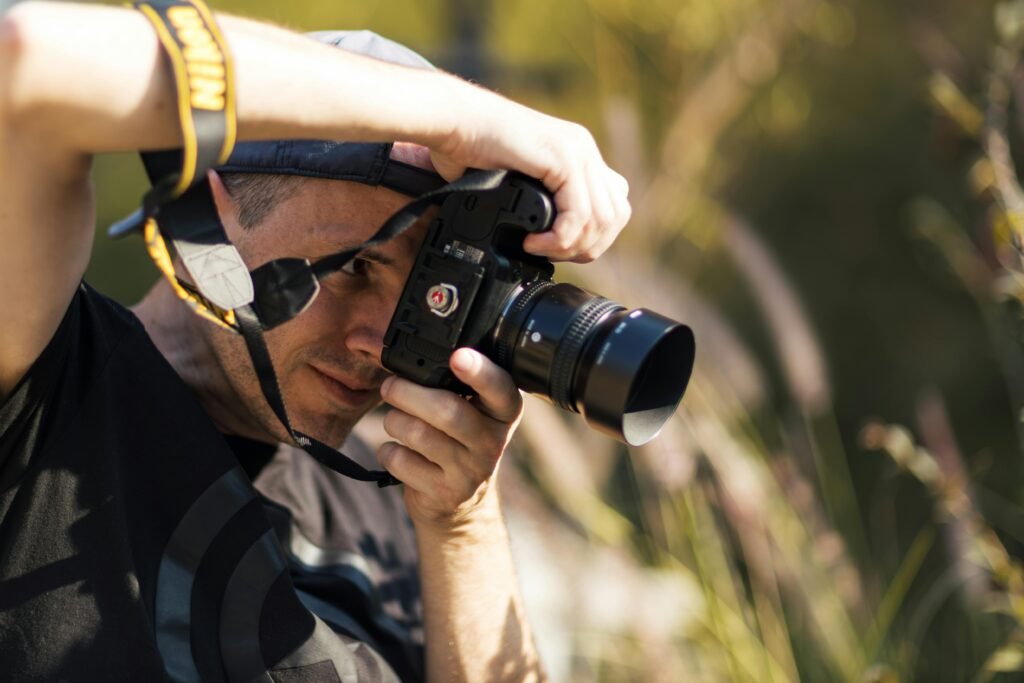 pexels photo 29548381 29548381 Close-up of a male photographer using DSLR camera outdoors, focusing on nature.